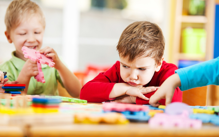 Angry little boy looking at puzzles.
